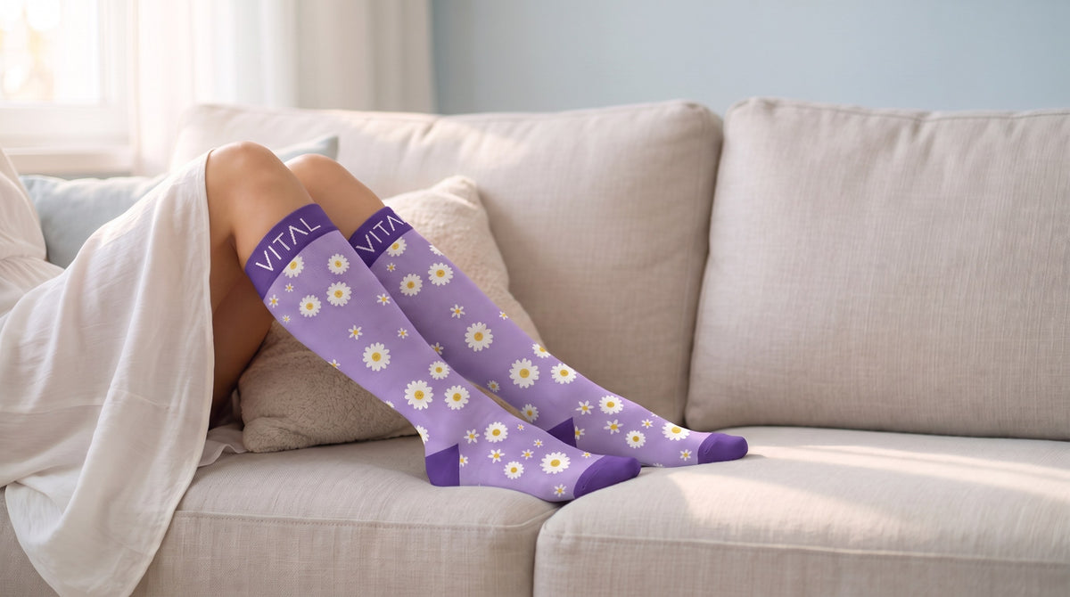 Daisy knee-high compression socks, white throw over the lap, legs resting on a cream couch