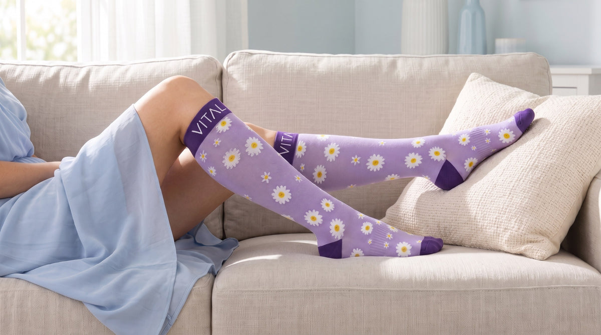 Daisy knee-high compression socks, light blue dress, reclining on a couch, one foot on a cushion